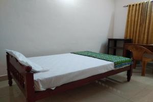 a small bed in a room with a table at SPOT ON Sana Tourist Home in Kollam