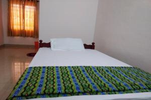 a bed with a colorful blanket on top of it at SPOT ON Sana Tourist Home in Kollam