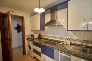 una cocina con armarios azules y blancos y fregadero en Apartamento Málaga Centro, en Málaga