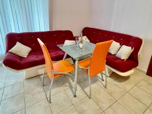 a living room with a glass table and orange chairs at Boris Apartments in Petrovac na Moru