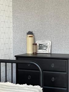 a black dresser with a picture on it next to a bed at Przeszklony Tiny House w Lesie in Tomczyn