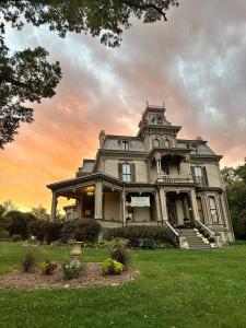 uma casa velha com um pôr-do-sol ao fundo em Garth Woodside Mansion Bed and Breakfast em Hannibal
