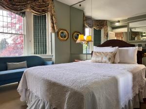 a bedroom with a bed and a couch and windows at Prior Castle Inn in Victoria