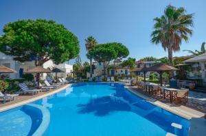 einen Pool mit Stühlen und Sonnenschirmen in einem Resort in der Unterkunft Alkyoni Beach Hotel in Naxos Chora