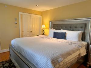 una camera da letto con un grande letto con lenzuola bianche e cuscini blu di Prior Castle Inn a Victoria