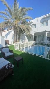 um quintal com uma piscina e uma palmeira e uma casa em درة العروس فيلا الذهبي 38 em Durat Alarous