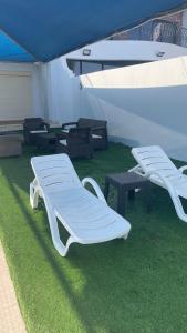 two white benches and tables in a room with grass at درة العروس فيلا الذهبي 38 in Durat Alarous