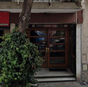 una puerta a un edificio con un árbol delante en 3 ambientes en Almagro. Excelente ubicación en Buenos Aires