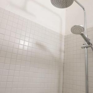 um chuveiro na casa de banho com azulejos brancos em Ubytovanie v Kláštore - Apartmány em Rožňava