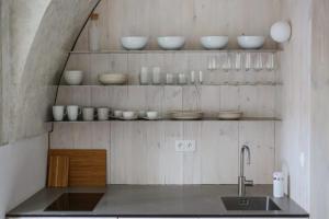 a kitchen with a sink and bowls on shelves at Ubytovanie v Kláštore - Apartmány in Rožňava