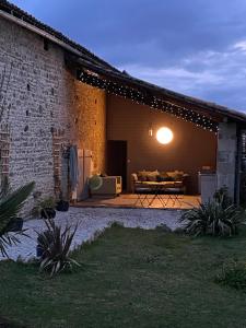 a backyard with a patio with a couch and a table at Le Vieux Renard in Vieux-Ruffec