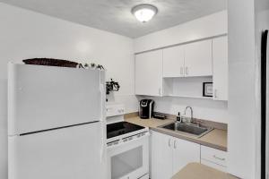 a kitchen with white cabinets and a white refrigerator at Victoria Park Regency in Fort Lauderdale