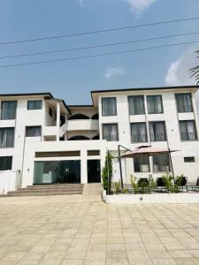un grand bâtiment blanc avec des bancs devant lui dans l'établissement Luxury Apartment with Pool, McCarthy hill, à Accra