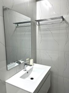 La salle de bains blanche est pourvue d'un lavabo et d'un miroir. dans l'établissement Luxury Apartment with Pool, McCarthy hill, à Accra