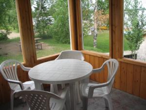 Betula Lake Resort في Seven Sister Falls: طاولة بيضاء وكراسي في غرفة بها نوافذ