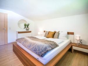 ein Schlafzimmer mit einem großen weißen Bett und Holzboden in der Unterkunft AlpenLuxus' PANORAMA Appartement with car park and balcony in Mayrhofen