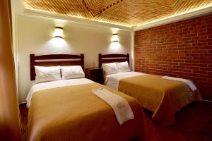 - 2 lits dans une chambre avec un mur en briques dans l'établissement Hotel Santa Irene, à Cholula
