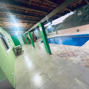 a swimming pool with green poles in a building at Chácara Li&Mazinho in Ibiúna