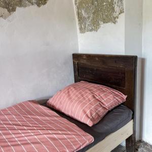 una cama con una almohada roja encima en Ubytovanie v Kláštore - Hostel, en Rožňava