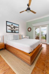 a bedroom with a large bed with a ceiling fan at Blue Roatan Resort in West Bay