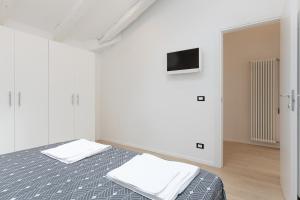 a white room with a bed and a tv at La casa di Po' in Trieste