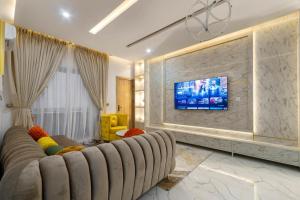 a living room with a couch and a tv on a wall at Emray Shortlets apartment in Lekki