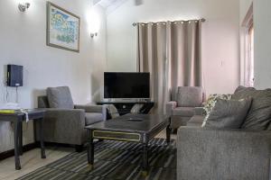 a living room with a couch and chairs and a tv at Best E Villas Providence in Christ Church