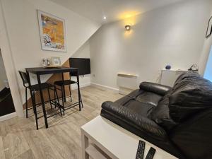 a living room with a leather couch and a table at 1 Bed House Luton town center in Luton