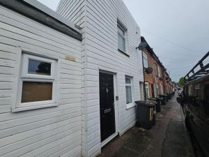 a white building with a black door and windows at 1 Bed House Luton town center in Luton
