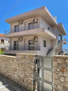 a house behind a stone wall with a gate at Acqua Blu Blu apartment in Koroni