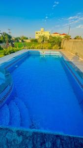 a large blue swimming pool with a building in the background at Luxury Farmhouse for Stay and Events in Lahore