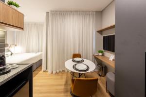 a room with a bed and a table in a room at Charlie NIK Pinheiros - Soft Opening in Sao Paulo