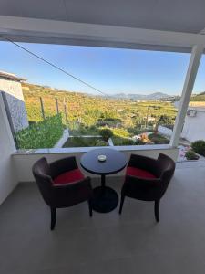 a room with two chairs and a table and a large window at Andi's GuestHouse in Sarandë
