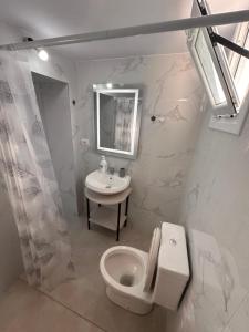a white bathroom with a toilet and a sink at Andi's GuestHouse in Sarandë +55 photos