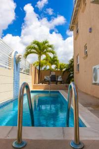 a swimming pool in the middle of a building with palm trees at Best E Villas Providence Ch Ch in Christ Church