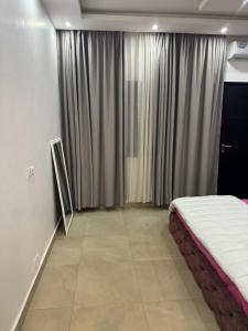 a bedroom with a bed and a window with curtains at Fabyimmo in Dakar