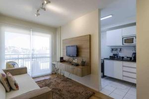 a kitchen and living room with a couch and a television at Apt⁰ aconchegante. Condomínio Menara in São Paulo