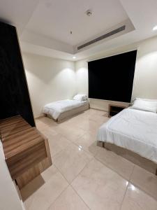 a bedroom with two beds and a flat screen tv at شقة 3 غرف وصالتين in Riyadh