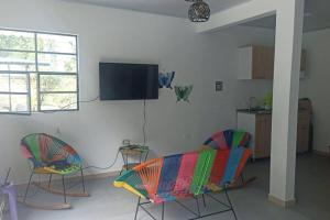 a living room with two chairs and a flat screen tv at Cabaña Mi Chelita in Ibagué