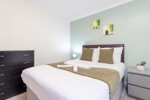 a bedroom with a large bed with white sheets and green pillows at Newly refurbed, 5BR, Sleeps 12 in Northampton