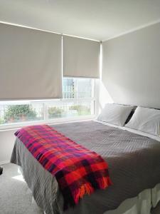ein Schlafzimmer mit einem Bett mit einer karierten Decke darauf in der Unterkunft Acogedor departamento en Temuco in Temuco