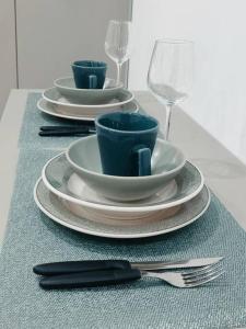 Tres tazas y platillos en una mesa con copas de vino. en Flat 305 Porto Prime com Rooftop e Piscina, en Porto de Galinhas