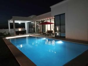 a swimming pool at night in front of a house at Villa turquoise in Mezraya