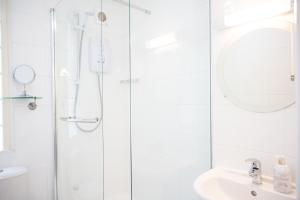 uma casa de banho branca com um chuveiro e um lavatório. em Northern Hideaways, Lockup Mews em Bellingham