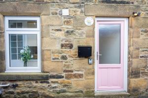 a pink door and windows on a stone building at Northern Hideaways Lockup Mews, Bellingham in Bellingham