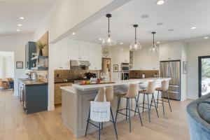 a kitchen with white cabinets and bar stools at Rancho Robles by AvantStay Vineyard Villa w Views Pool Privacy in Paso Robles