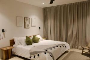 um quarto com uma cama com lençóis brancos e almofadas verdes em Casa Delirio - Beautiful and Modern em Refundores