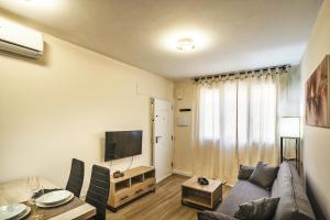Una sala de estar con un sofá y un televisor. en PLAYA SUITES a 50 metros de la playa, en Puerto Sagunto