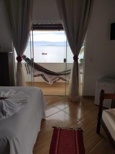 um quarto com uma cama e vista para o oceano em Suítes Encanto do Pai em Praia de Araçatiba