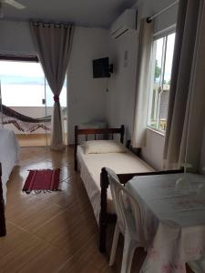 1 dormitorio con 2 camas, mesa y ventana en Suítes Encanto do Pai, en Praia de Araçatiba